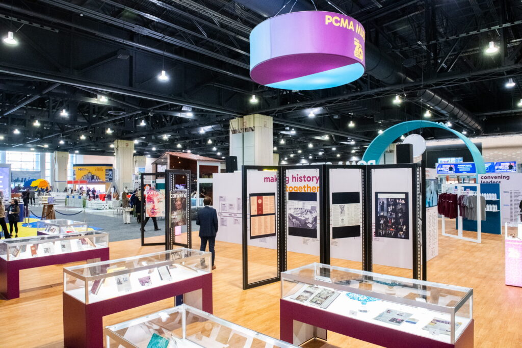 Open trade show floor showcasing custom Source One event installations, suspended signage, and experiential conference environments.