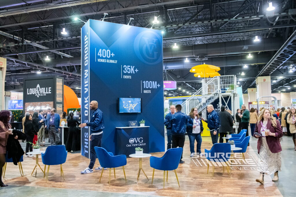 Large-scale trade show exhibit with branded tower display and meeting area