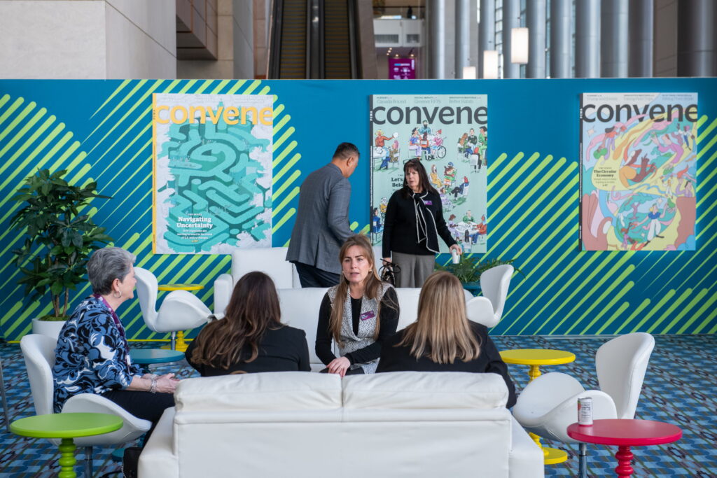 Source One Events team engaging attendees inside the PCMA Convening Leaders networking pavilion with vibrant teal environmental branding.