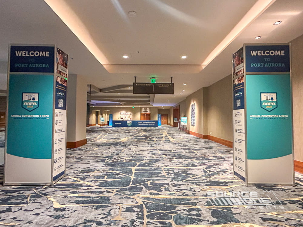 Modular octanorm tower displays with blue and white branding providing directional signage throughout the conference venue.