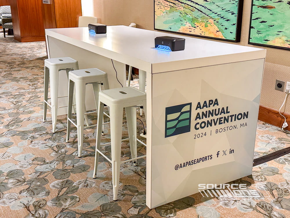 Bright networking café featuring white high-top tables, modern seating, and branded conference environment.