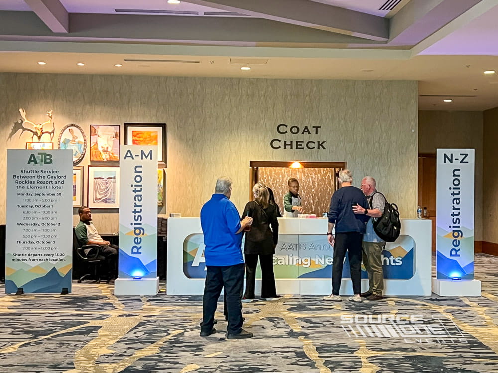 Modern registration desk featuring blue branded graphics, attendee service counters, and digital information displays.