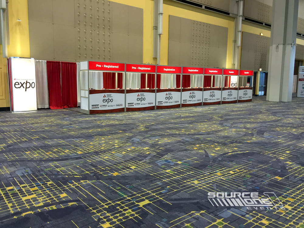 Registration area with red branded counters, attendee queue management, and convention center check-in stations.