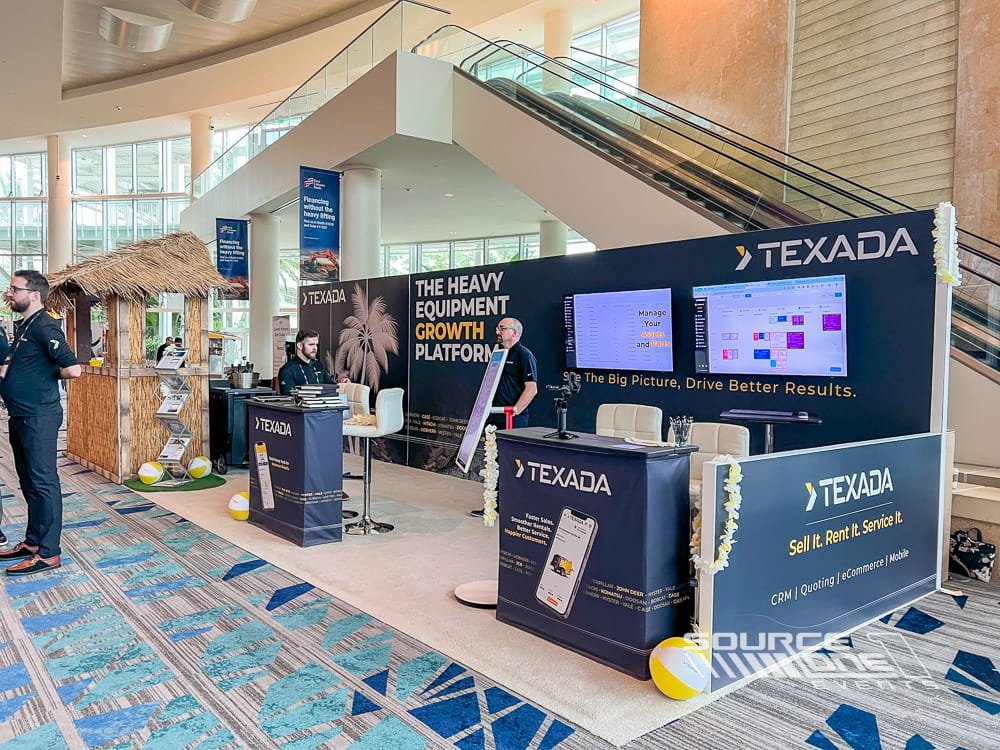 Construction technology exhibit featuring digital displays, branded graphics, and modern product demonstration counters.