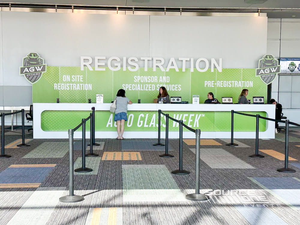 Modern registration area featuring green branded graphics, attendee check-in counters, and large welcome signage.