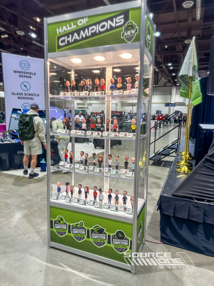 Tall illuminated product display case featuring branded shelving and merchandise within the trade show exhibit.
