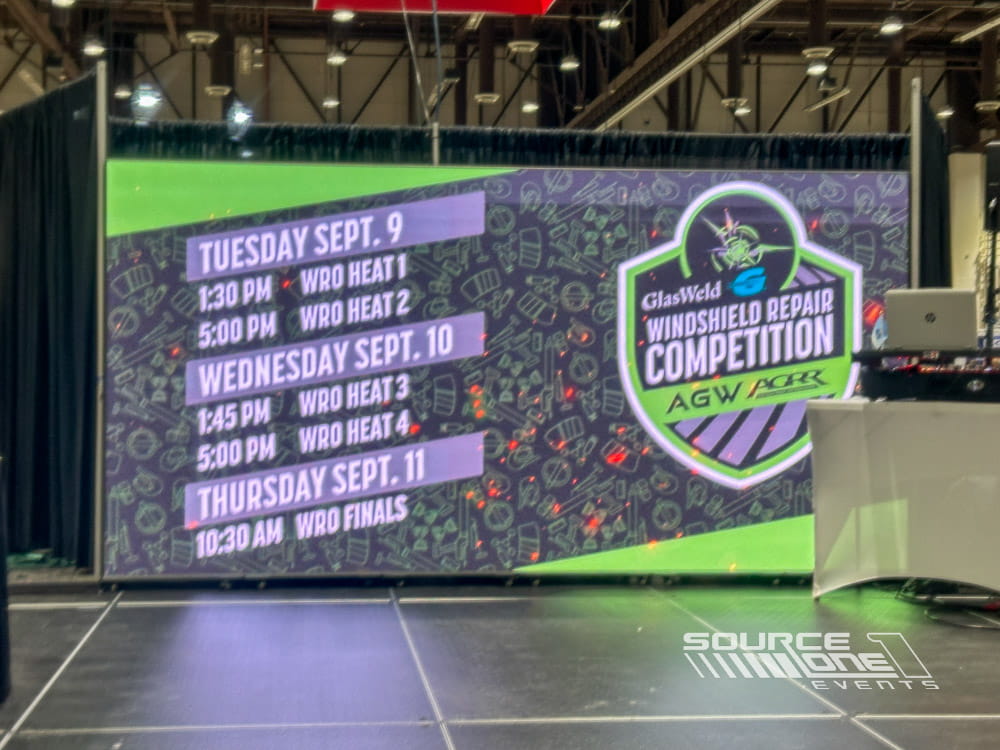 Large LED video wall displaying conference schedule, colorful event branding, and interactive attendee information.