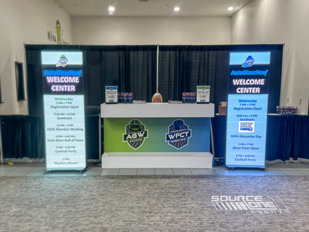 Modern conference registration area with branded digital welcome displays, attendee check-in counters, and organized queuing lanes.