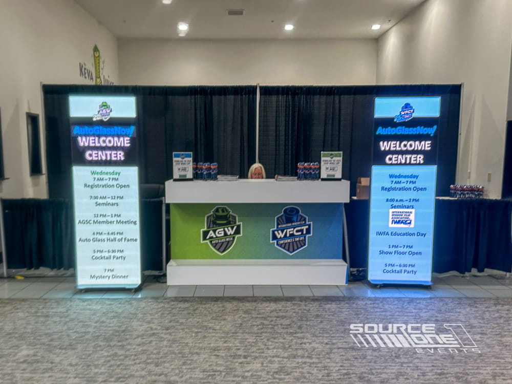 Contemporary registration desk with digital displays, attendee service counters, and branded conference graphics.