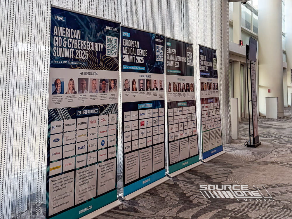 Large banner stand display showcasing event information inside a convention center hallway.