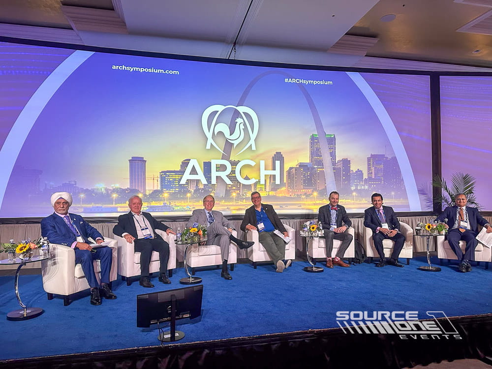 Panel discussion stage featuring large branded LED backdrop, presenter seating, and professional conference production.