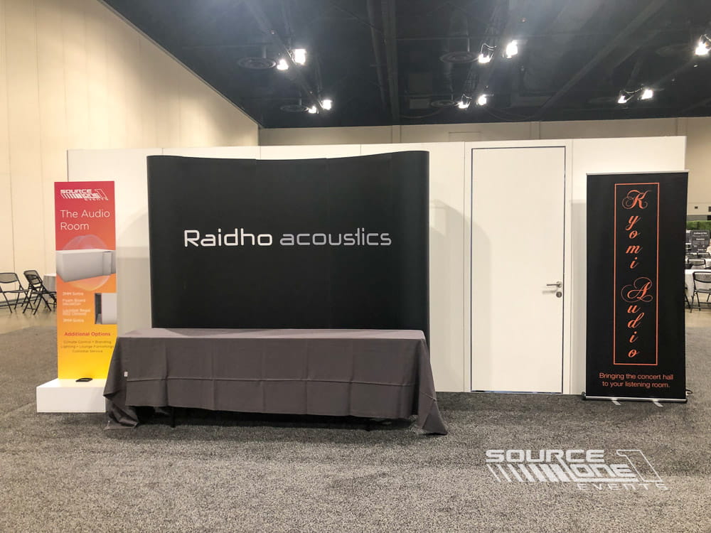 Custom-built sound isolation room with acoustic wall panels and modern lighting, designed for private audio demonstrations at a trade show.