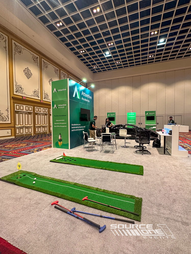 Contemporary trade show booth with green branding, digital presentation screens, and open visitor interaction space.