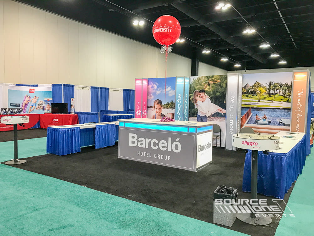 Hospitality industry exhibit featuring colorful destination graphics, open reception area, and custom trade show booth design for attendee engagement.