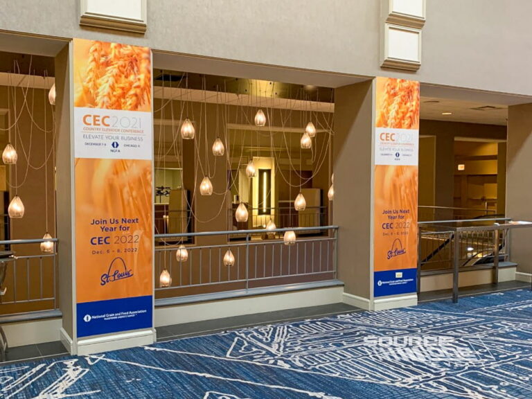 Orange and white column wraps featuring conference branding and sponsor messaging inside a convention center lobby.