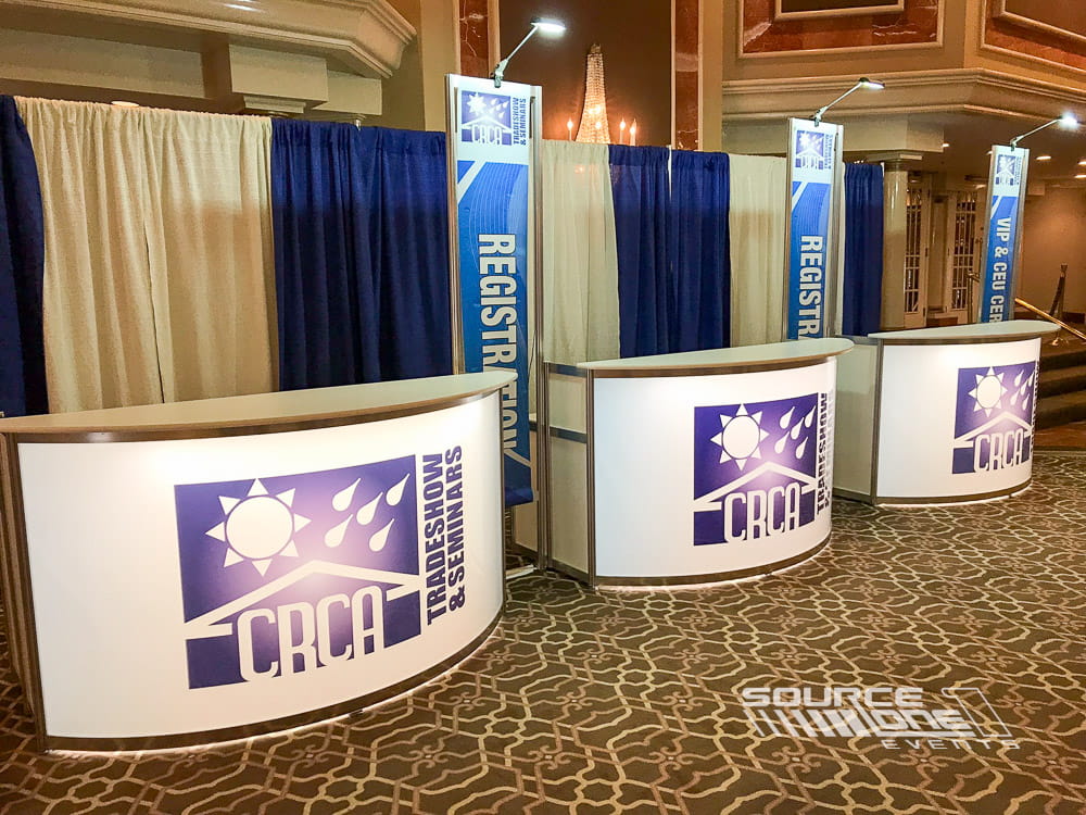 Blue branded registration counter with professional attendee check-in stations and conference welcome signage.