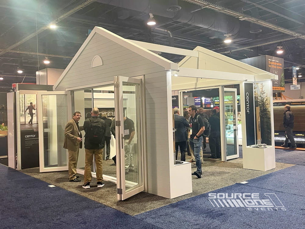 Residential-style custom exhibit featuring white architectural structures, open meeting areas, and premium exhibit fabrication for a trade show environment.