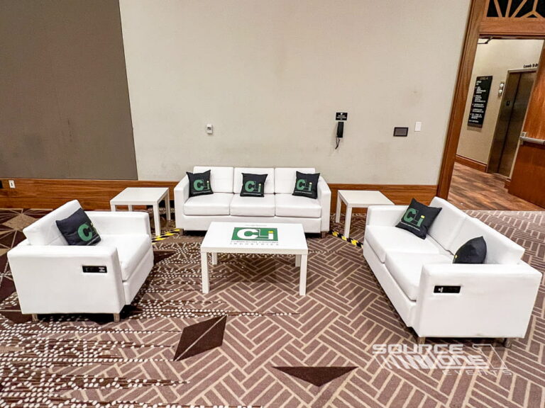 Modern charging lounge with white upholstered seating, integrated charging stations, and open networking space for event attendees.
