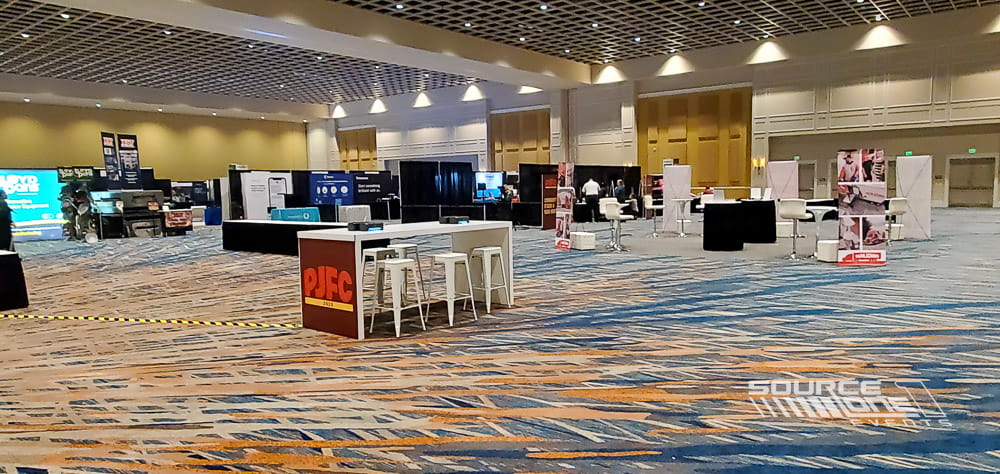High-top charging table with integrated power outlets and contemporary furniture designed for attendee networking and device charging.