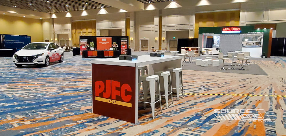 Custom charging table positioned within a trade show exhibit, providing convenient charging access and casual meeting space.