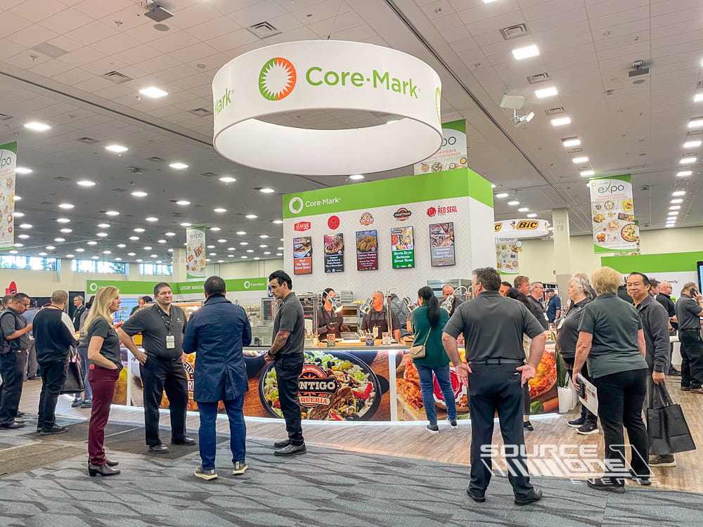 Large round hanging sign displaying Core-Mark branding above the exhibit floor to attract attendees.
