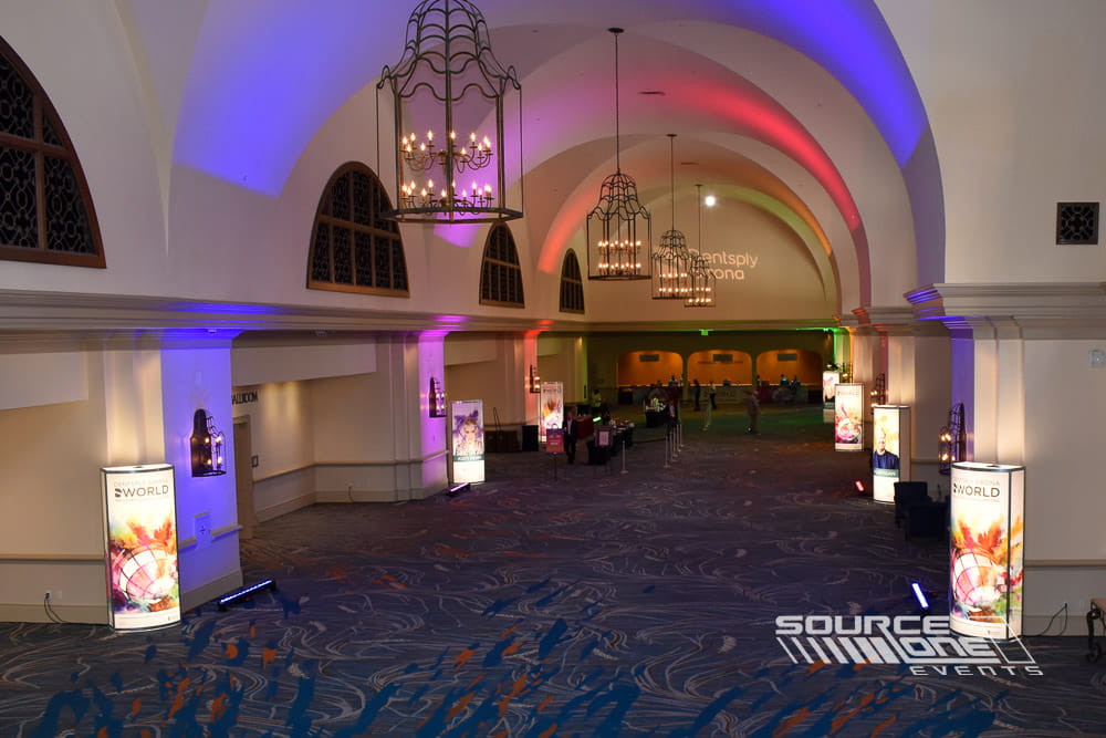 Purple illuminated architectural columns enhancing conference entrances with elegant branded lighting and wayfinding.