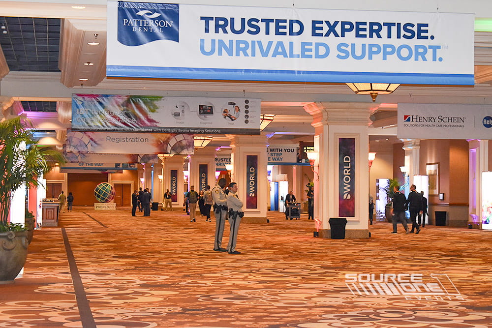 Wide overhead banner installed across the convention concourse promoting sponsors and conference branding.