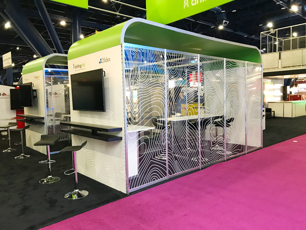 Corner view of a custom Drillinginfo exhibit with meeting areas and digital displays.