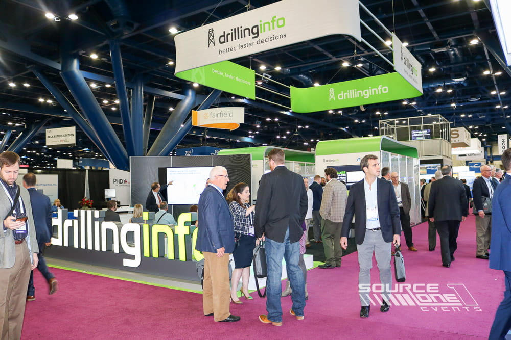 Multiple overhead hanging signs identifying the Drillinginfo exhibit booth from across the exhibition hall.