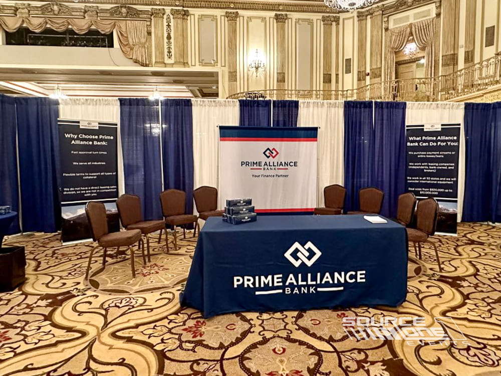 Branded conference exhibit table featuring custom printed table cover and promotional materials for attendee engagement.