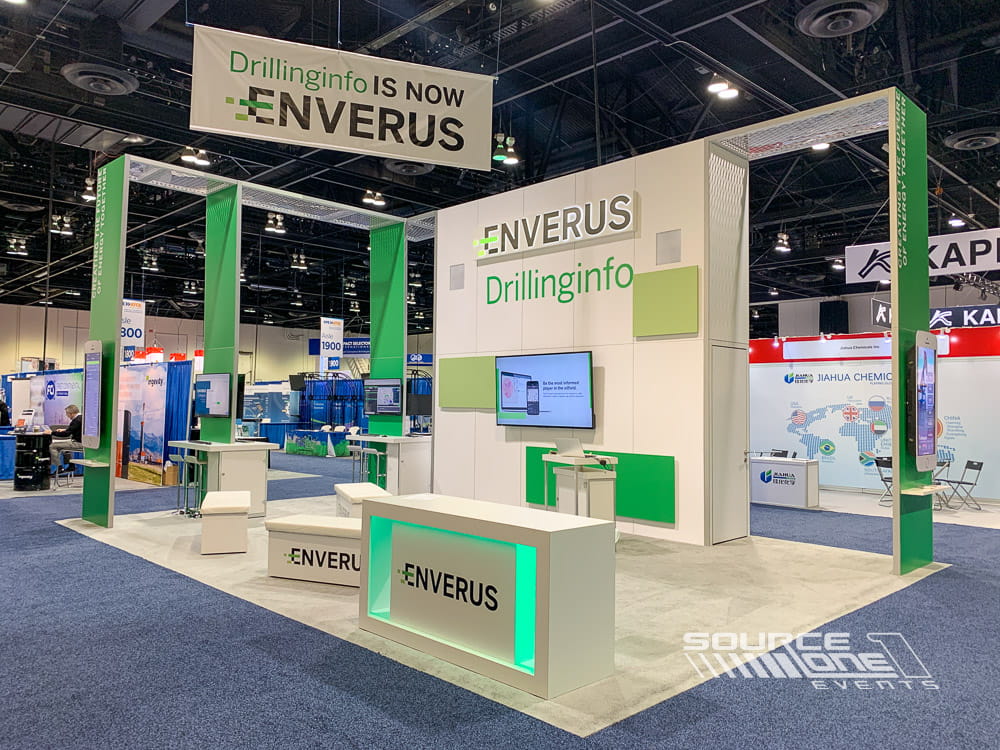 Large green and white custom trade show exhibit featuring suspended signage, digital displays, and premium exhibit fabrication.