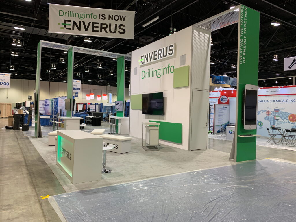 Green and white custom exhibit with overhead hanging signage, integrated meeting areas, and premium trade show architecture.