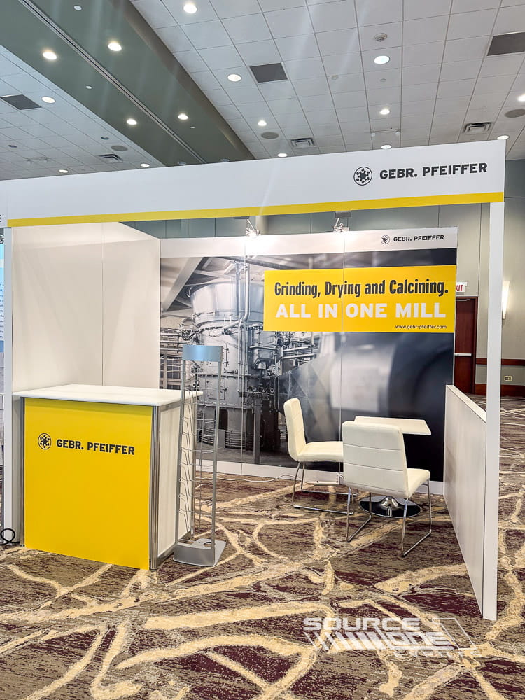 Bright custom trade show booth featuring clean white architectural walls, product displays, corporate branding, and professional exhibit design by Source One Events.