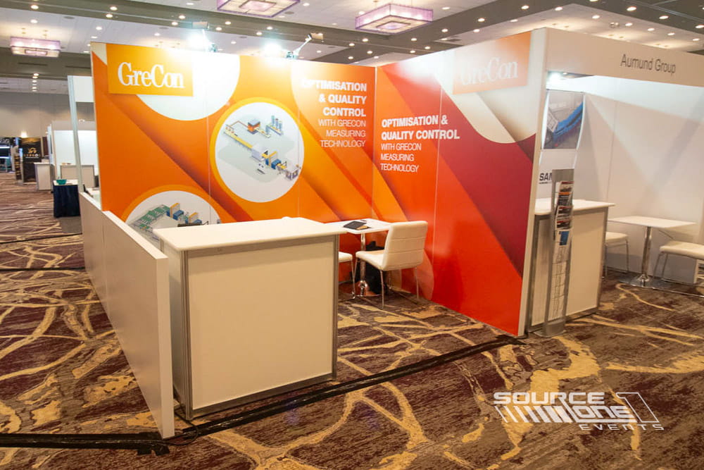Vibrant red and orange custom trade show booth featuring reception counter, bold graphics, and modern exhibit architecture.