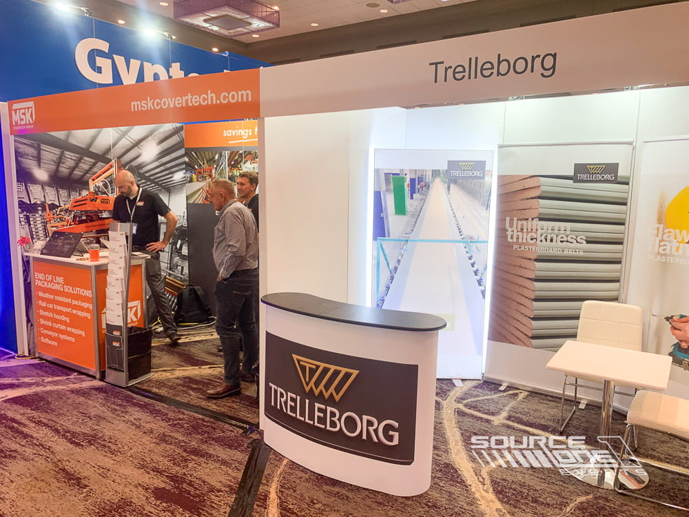 Corporate trade show booth with product showcases, architectural graphics, and open networking space.