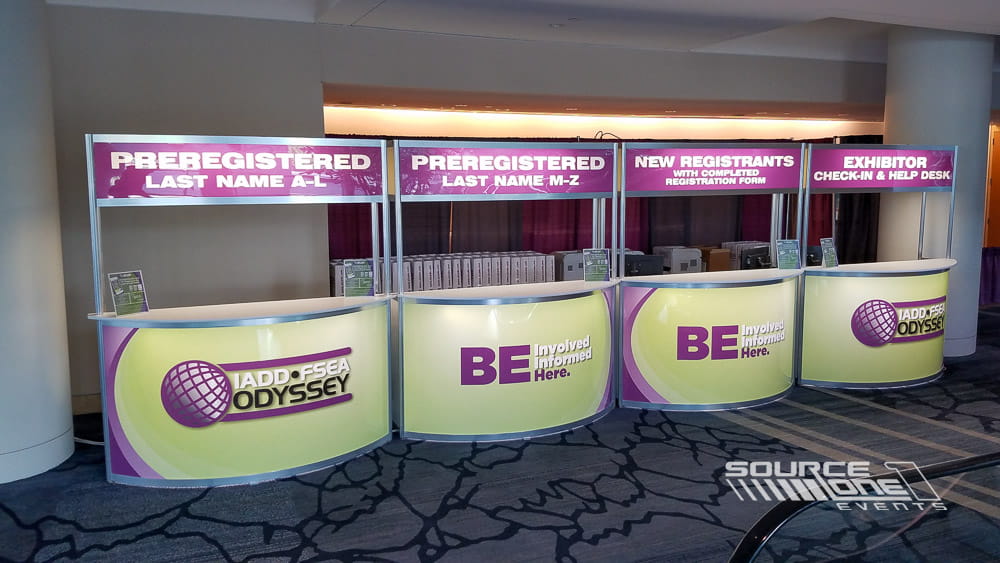 Registration entrance featuring illuminated magenta branding, attendee check-in counters, and integrated wayfinding signage.