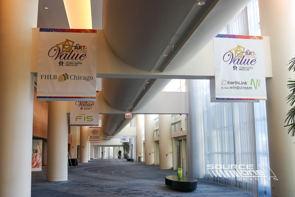 Multiple hanging fabric banners displaying conference branding throughout the convention center to improve visibility and wayfinding.