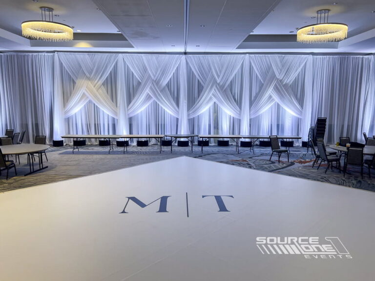 Beautifully draped stage backdrop with white fabric, premium lighting, and elegant event décor for conferences and corporate meetings.
