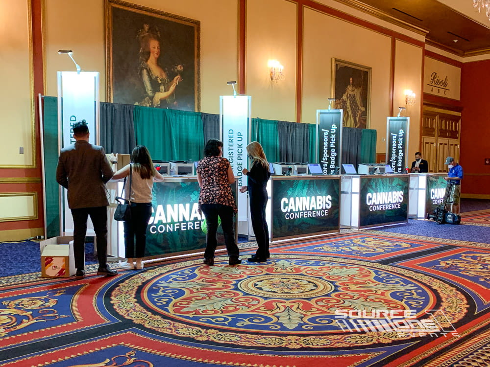 Custom branded registration counters with digital displays, attendee service stations, and modern conference check-in environment designed by Source One Events.