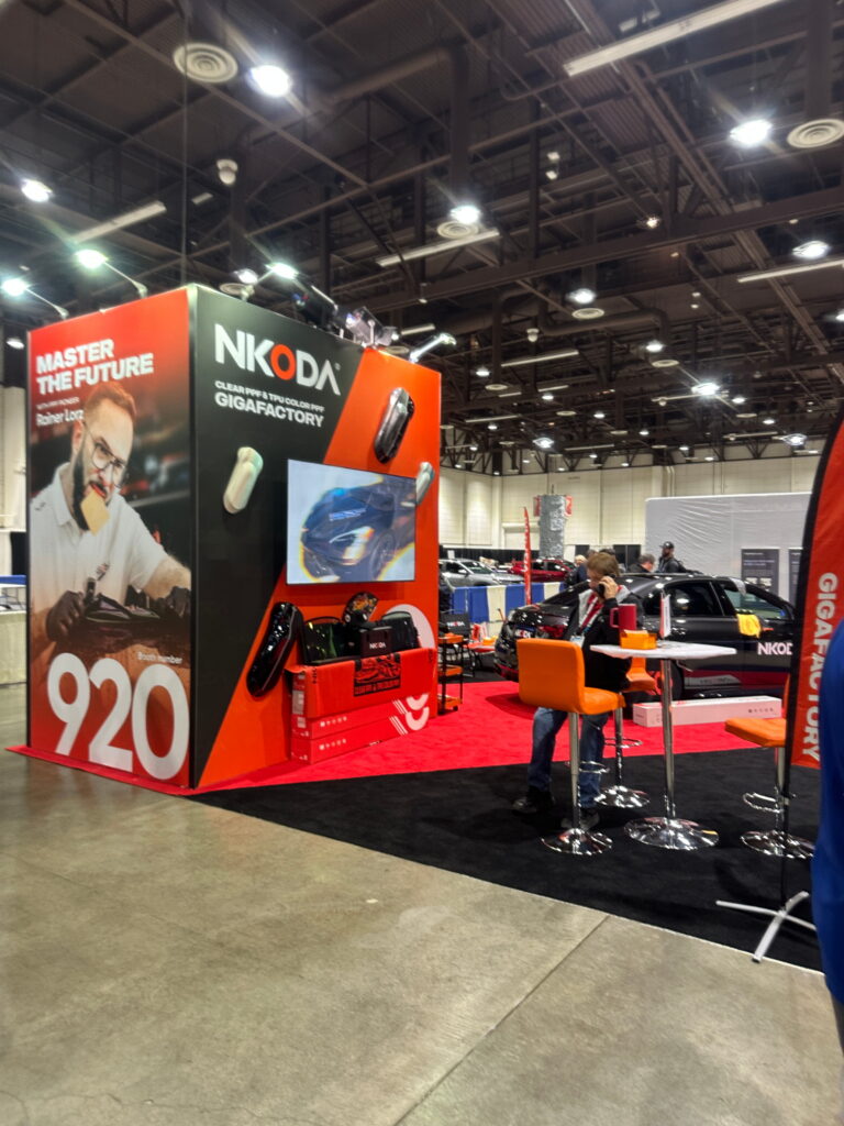 Large automotive exhibit featuring suspended signage, dramatic graphics, and immersive product displays within a convention hall.