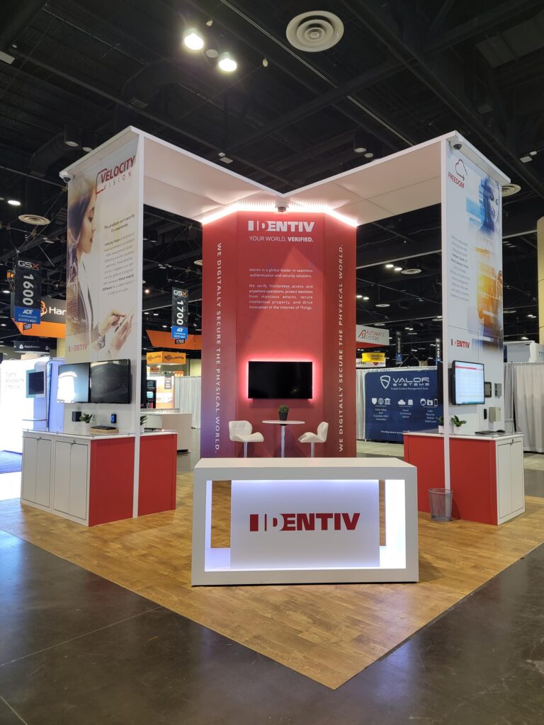 Tall architectural exhibit with bold red branding, integrated product displays, and premium custom booth construction.