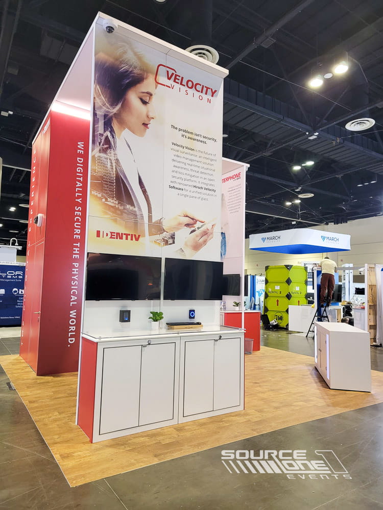 Premium custom exhibit with tall illuminated branding towers, modern exhibit fabrication, and open visitor engagement.