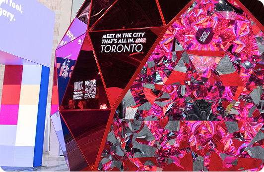 Immersive LED entrance installation with vibrant pink geometric graphics creating a dramatic experiential welcome at a major convention.