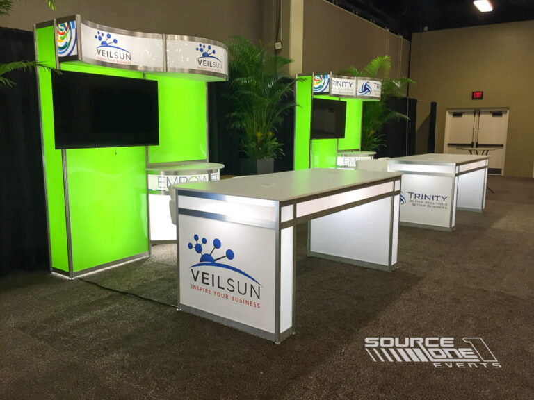 Bright green and white custom exhibit booth with integrated monitors, reception counters, and contemporary trade show architecture.