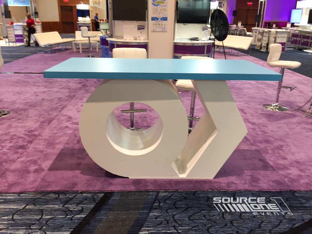 Custom branded table with integrated graphics for attendee engagement at a conference.