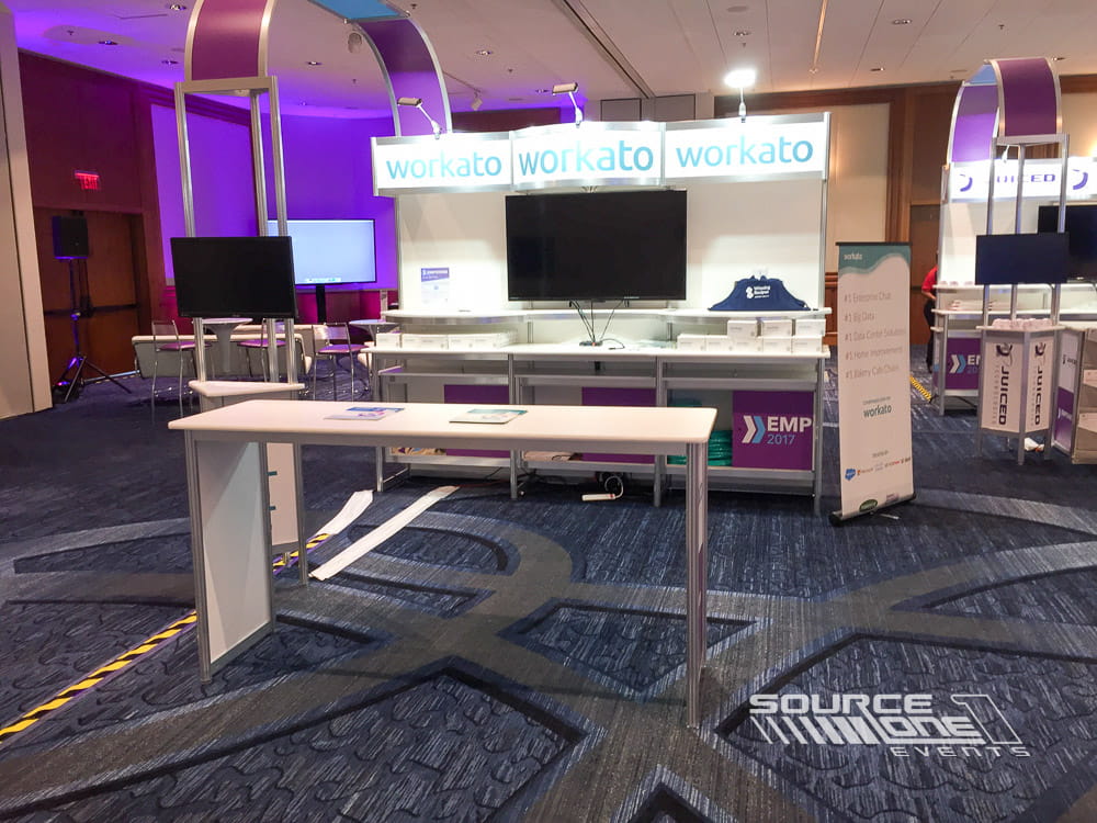 Modern interactive kiosk featuring digital displays, white counters, and branded graphics for attendee education and demonstrations.