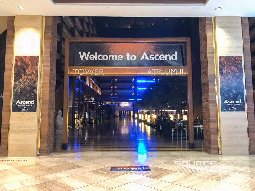Large illuminated hanging banner welcoming attendees into the branded conference environment.