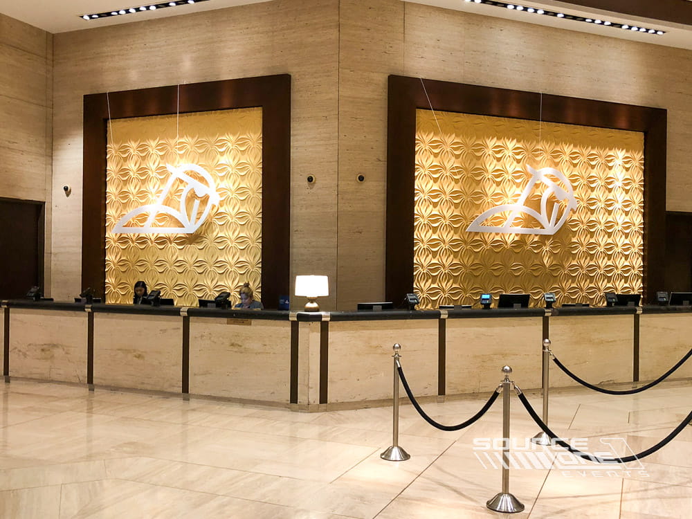 Warm backlit wall branding and suspended graphics creating an upscale event entrance experience.