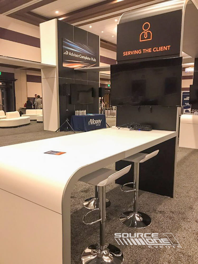 Contemporary networking counter with seating, technology integration, and branded event environment.