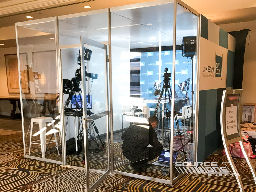 Glass-enclosed content creation room equipped with professional cameras, lighting, and podcast recording technology.